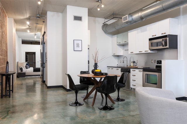 kitchen with appliances with stainless steel finishes, sink, a high ceiling, and white cabinetry