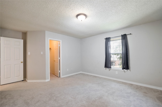 empty room featuring a textured ceiling and light colored carpet