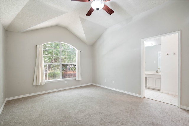 spare room with a textured ceiling, light carpet, and lofted ceiling