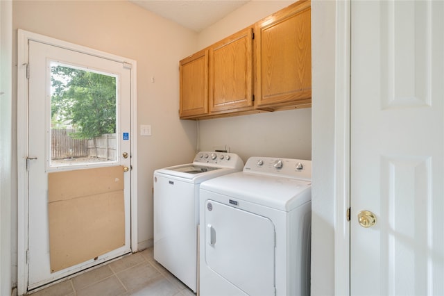 clothes washing area featuring separate washer and dryer, cabinets, and light tile patterned floors