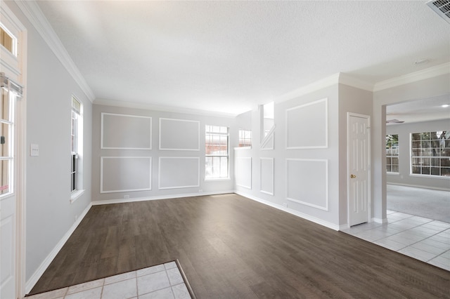 empty room featuring a textured ceiling, light tile patterned floors, and crown molding