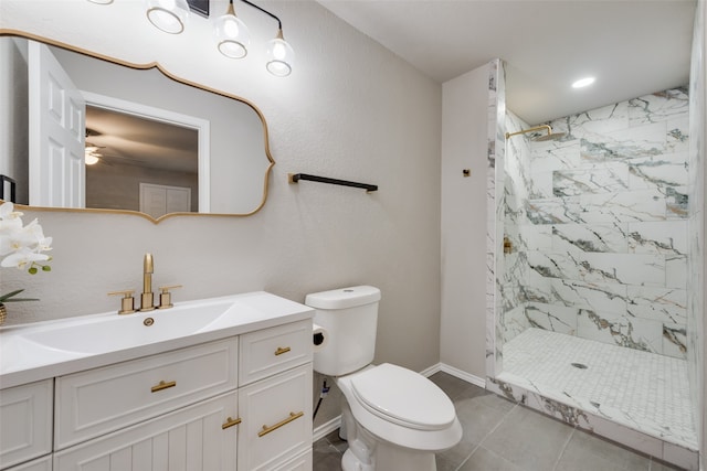 bathroom with a tile shower, vanity, tile patterned floors, and toilet