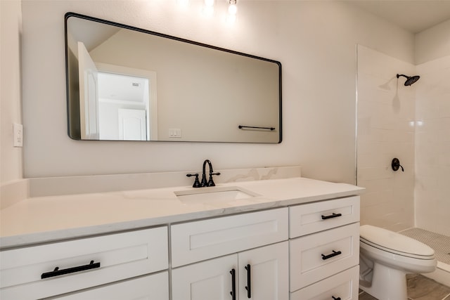 bathroom featuring vanity, tiled shower, and toilet