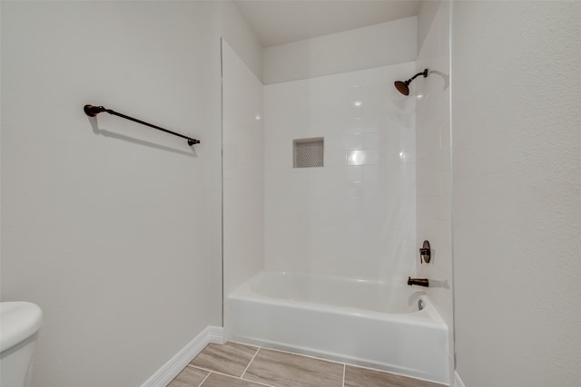 bathroom featuring tiled shower / bath combo, toilet, and tile patterned floors