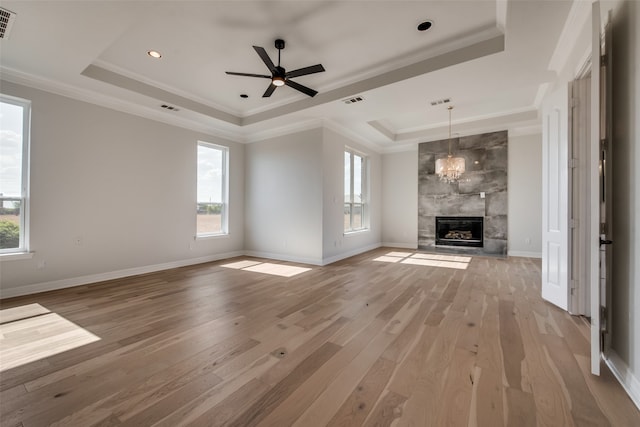 unfurnished living room with a high end fireplace, ornamental molding, a raised ceiling, and hardwood / wood-style floors