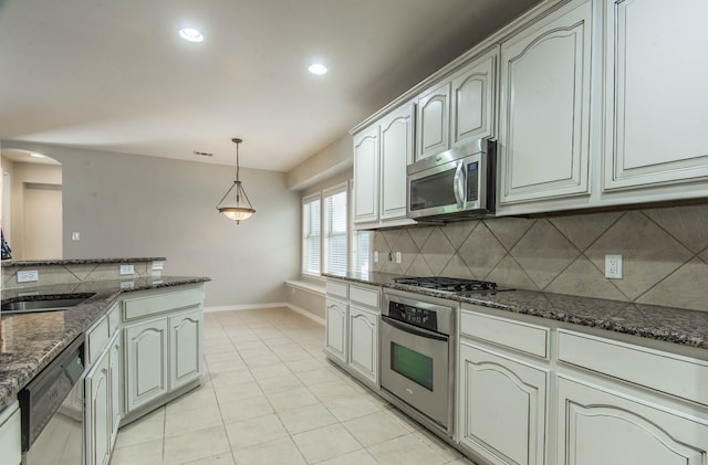 kitchen with appliances with stainless steel finishes, dark stone counters, and light tile patterned flooring