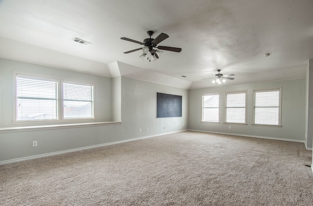 carpeted empty room with ceiling fan, a healthy amount of sunlight, and vaulted ceiling