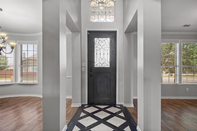 foyer entrance featuring dark wood-type flooring, a notable chandelier, and ornamental molding