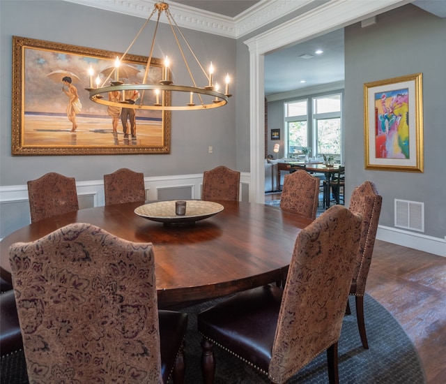 dining space featuring a notable chandelier, ornamental molding, and dark wood-type flooring