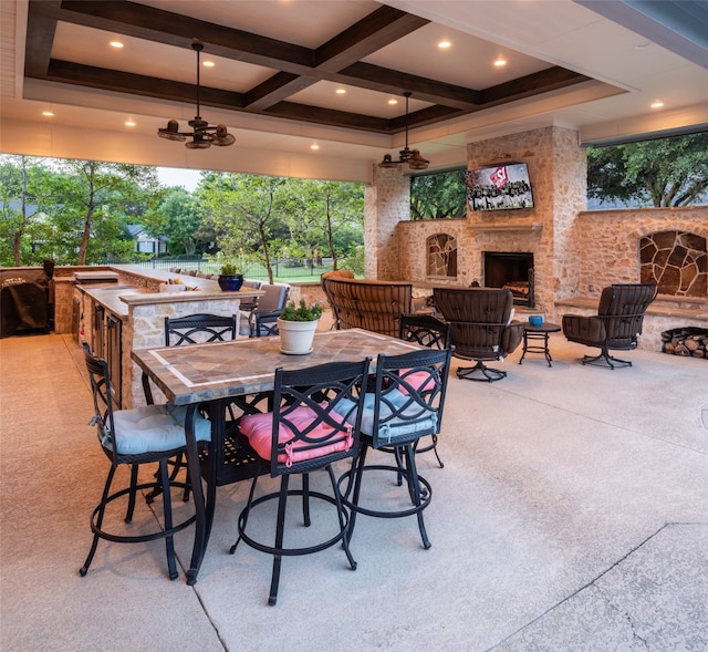 view of patio / terrace featuring ceiling fan, an outdoor stone fireplace, and outdoor dining area