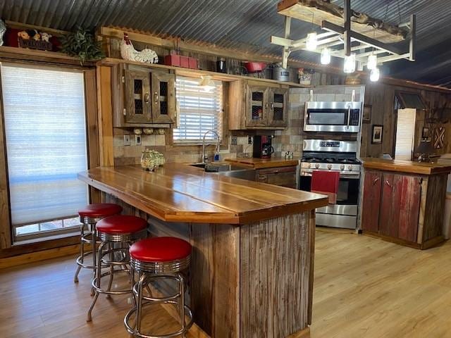 kitchen featuring kitchen peninsula, sink, stainless steel appliances, and light hardwood / wood-style flooring