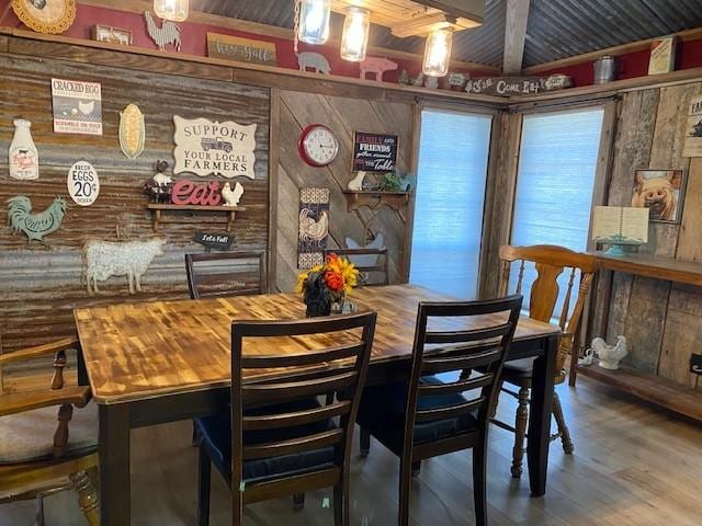 dining space with beamed ceiling, wood walls, and wood-type flooring