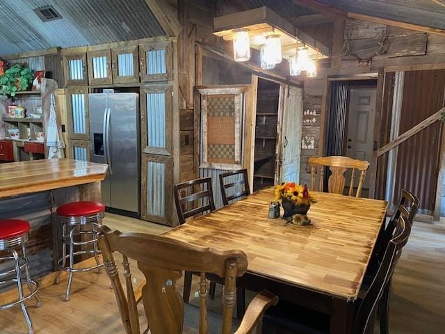 dining area featuring hardwood / wood-style flooring, wood walls, and vaulted ceiling