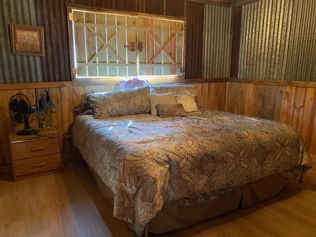 bedroom featuring wooden walls and hardwood / wood-style flooring