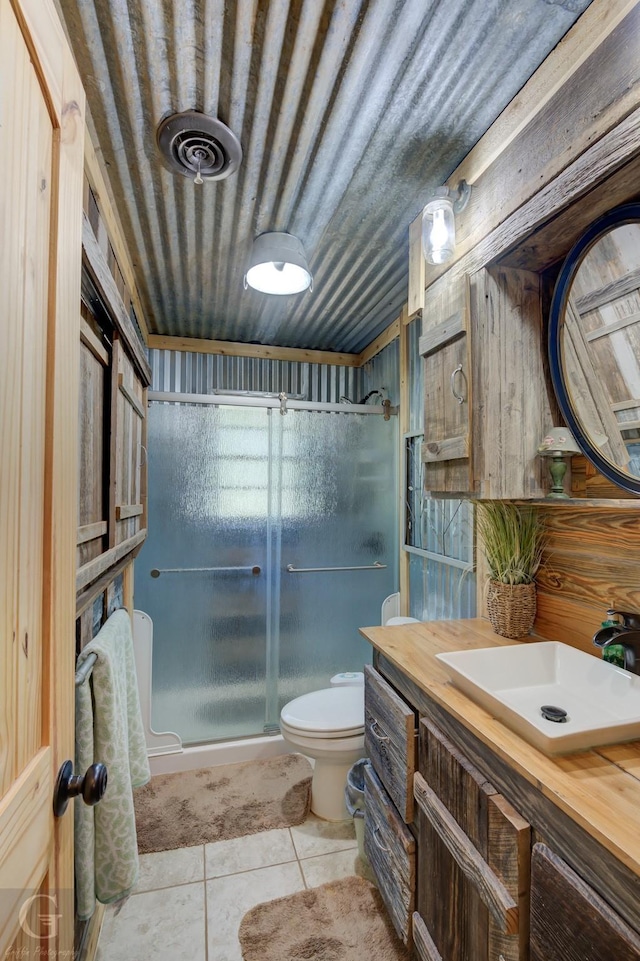 bathroom with tile patterned floors, toilet, vanity, and walk in shower