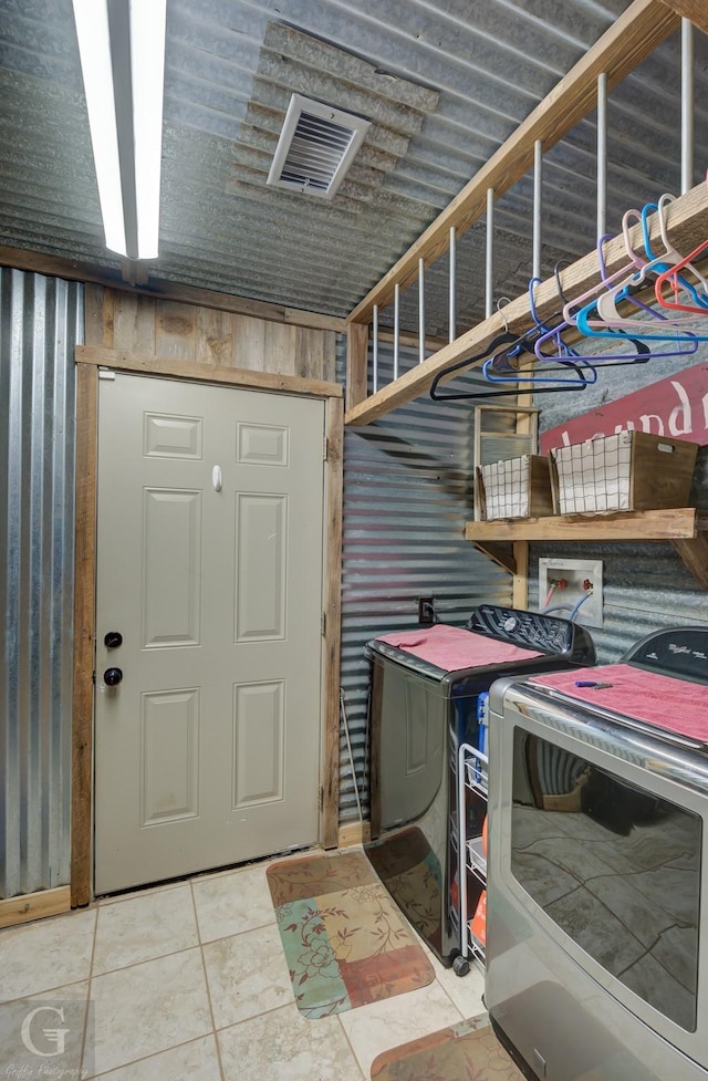 washroom with washing machine and clothes dryer, wood walls, and tile patterned flooring