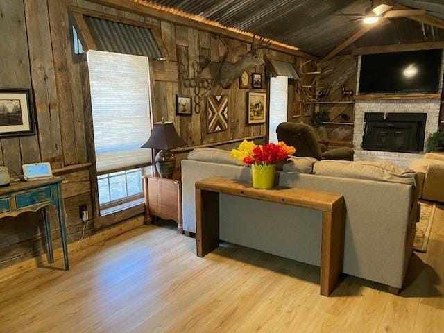 living room with wood walls, light hardwood / wood-style floors, and a brick fireplace