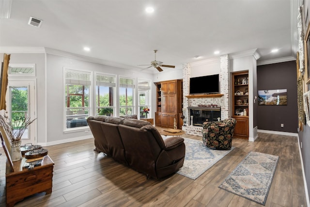 living room featuring a fireplace, hardwood / wood-style flooring, ceiling fan, and crown molding