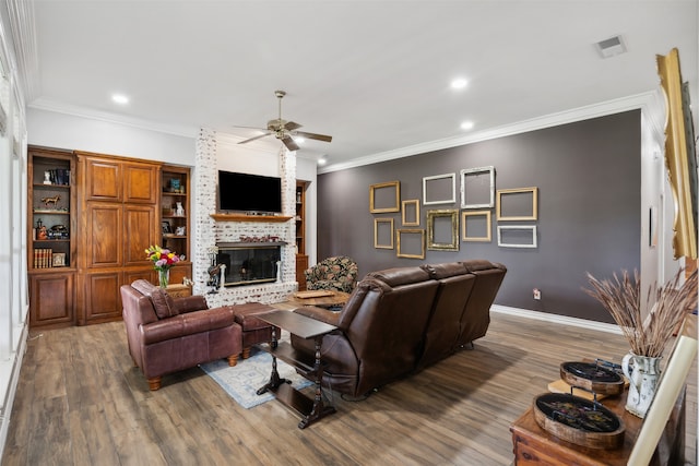 living room with a brick fireplace, hardwood / wood-style floors, crown molding, and ceiling fan