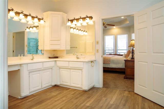 bathroom featuring vanity, hardwood / wood-style flooring, ceiling fan, and a raised ceiling