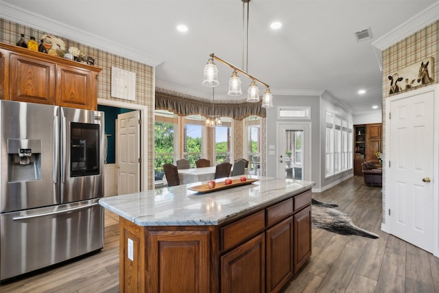 kitchen with a center island, hanging light fixtures, stainless steel fridge with ice dispenser, ornamental molding, and light wood-type flooring