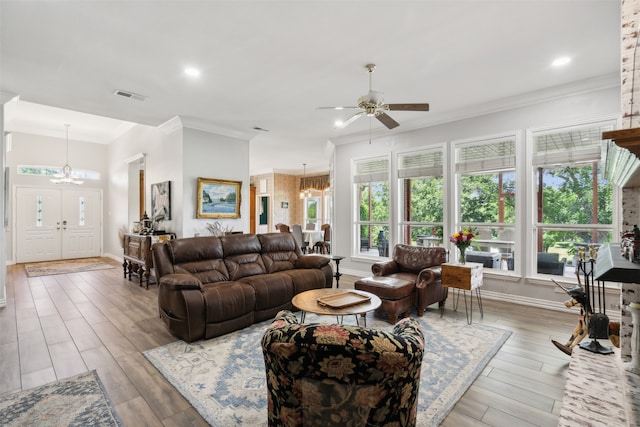 living room with wood-type flooring, ceiling fan with notable chandelier, and ornamental molding