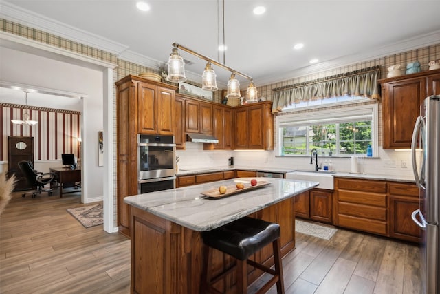 kitchen with sink, a kitchen island, appliances with stainless steel finishes, and pendant lighting