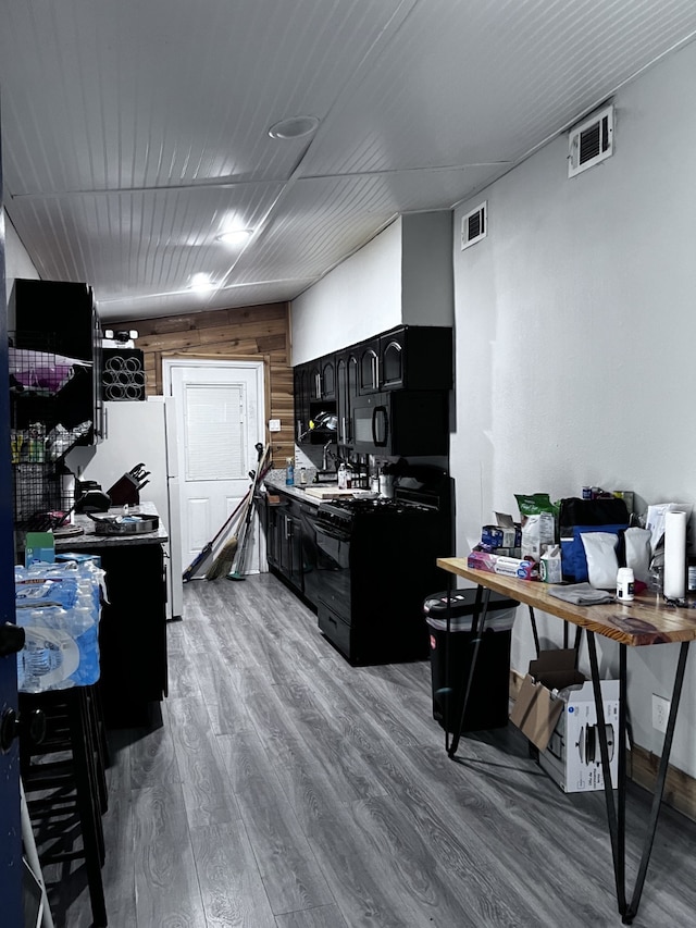 kitchen featuring white refrigerator, hardwood / wood-style flooring, and wooden walls