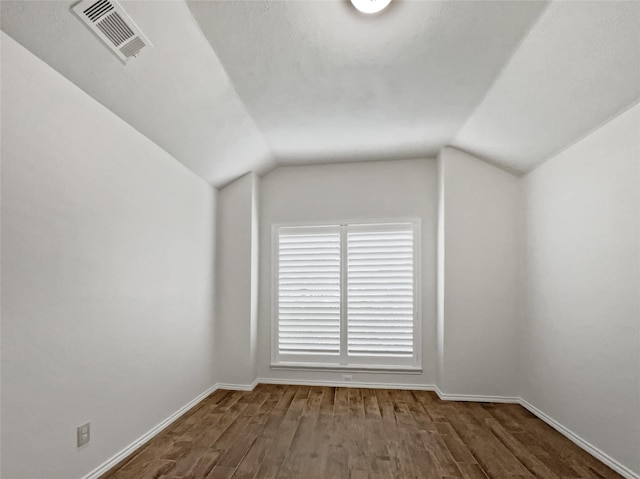 additional living space with dark wood-type flooring and vaulted ceiling