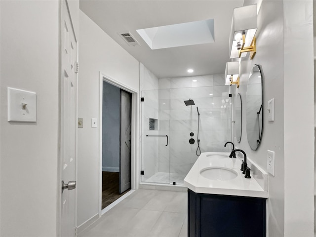 bathroom with a shower with door, a skylight, tile patterned floors, and vanity