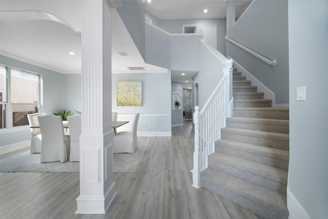 entrance foyer featuring light hardwood / wood-style floors, decorative columns, and crown molding