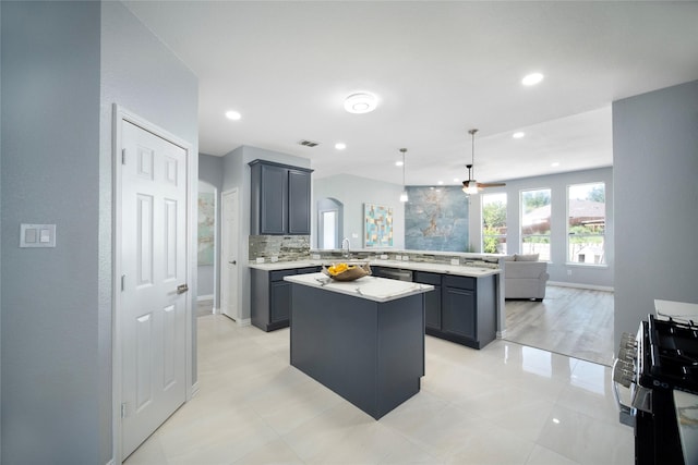 kitchen featuring kitchen peninsula, stove, ceiling fan, decorative light fixtures, and a center island