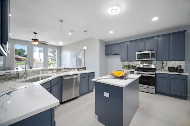 kitchen featuring a center island, sink, ceiling fan, light stone countertops, and appliances with stainless steel finishes