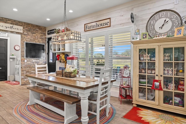 dining room with wooden walls, light hardwood / wood-style floors, and brick wall