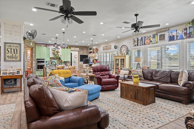 living room with ceiling fan, light wood-type flooring, and brick wall