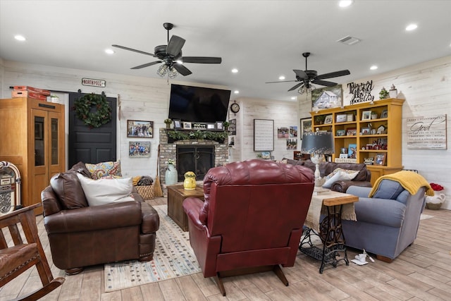 living room featuring ceiling fan, a fireplace, and light hardwood / wood-style floors