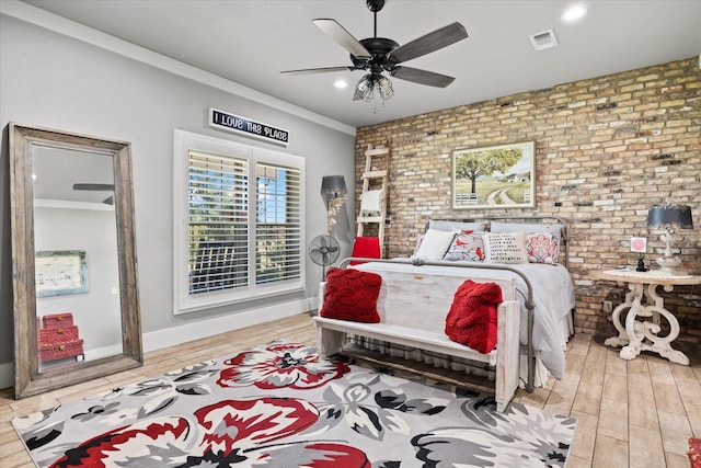 bedroom featuring light hardwood / wood-style flooring, ceiling fan, ornamental molding, and brick wall