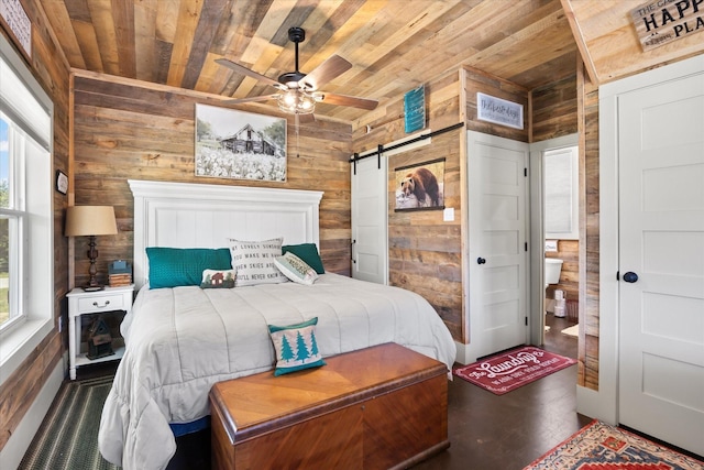 bedroom with wood walls, a barn door, and wood ceiling