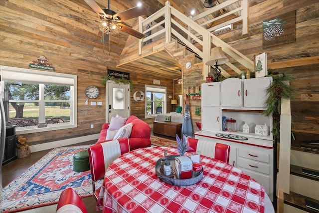 dining room featuring high vaulted ceiling, ceiling fan, wooden ceiling, and wooden walls