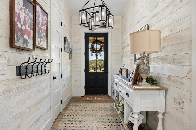 mudroom featuring an inviting chandelier and wooden walls