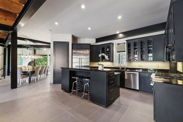 kitchen with stainless steel appliances, decorative light fixtures, light tile patterned floors, beam ceiling, and a center island