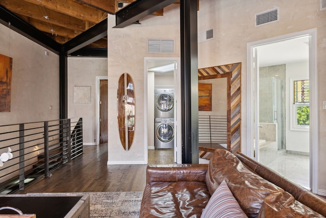 living room with dark hardwood / wood-style floors, beamed ceiling, stacked washer and clothes dryer, and high vaulted ceiling