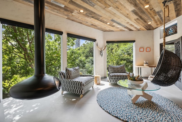 sunroom / solarium with wooden ceiling, a wealth of natural light, and a wood stove