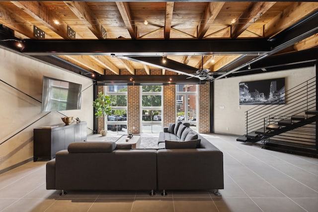 tiled living room featuring beamed ceiling, brick wall, wooden ceiling, and ceiling fan