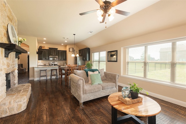 living room featuring dark wood-type flooring, ceiling fan, and a stone fireplace