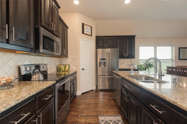 kitchen featuring light stone counters, stainless steel appliances, sink, and dark brown cabinets