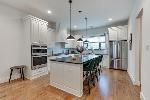 kitchen with light hardwood / wood-style floors, premium range hood, backsplash, and stainless steel appliances