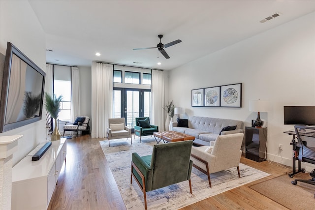 living room with expansive windows, ceiling fan, french doors, and light hardwood / wood-style flooring