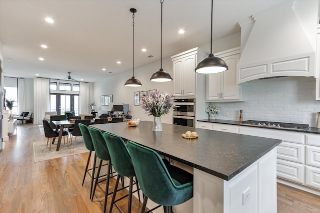 kitchen with white cabinetry, custom range hood, light hardwood / wood-style flooring, and a kitchen island