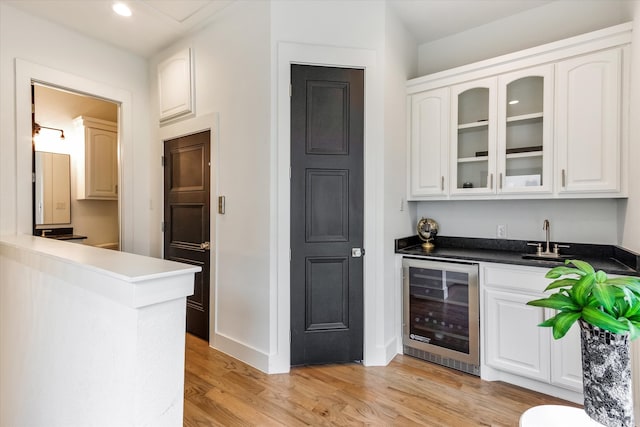 kitchen with white cabinetry, light hardwood / wood-style floors, sink, and wine cooler